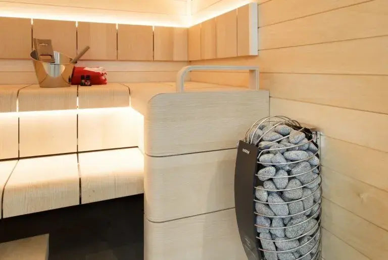Modern sauna interior with wooden benches and a rock-lined sauna heater.