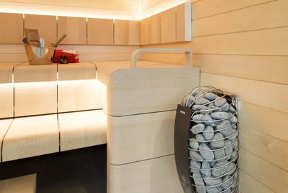 Modern sauna interior with wooden benches and a rock-lined sauna heater.